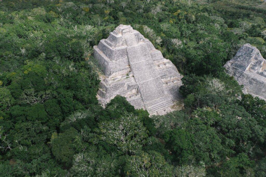 Mejor época para viajar a México 17 Pirámide maya rodeada de vegetación densa en un paisaje natural. La estructura refleja la rica herencia cultural de México.